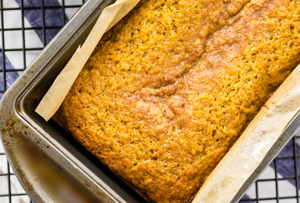 Moist loaf of richly spiced pumpkin bread just coming out of the oven, perfectly golden brown